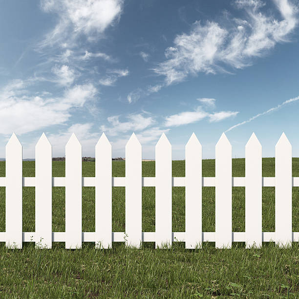 istock Green field and white fence 457445125