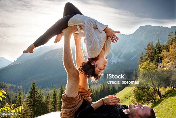 Man On His Back Balancing A Woman Laying On His Feet Stock Photo - Download Image Now