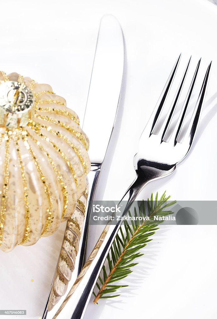 Festive  table setting with Christmas ornaments Festive  table setting with Christmas ornaments and copy space for text. Christmas fir tree branch and golden ball  on white plate isolated on white background, close up. Arranging Stock Photo