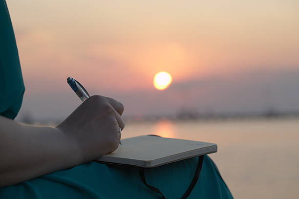 kobieta pisania na jej dzienniczka o zachodzie słońca - letter writing note pad handwriting zdjęcia i obrazy z banku zdjęć