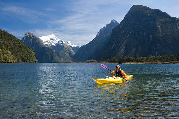 Young man kayaking in peaceful lake with mountains in background