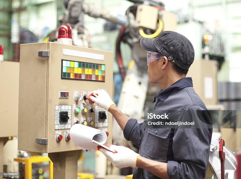 Industrial engineer in factory Manufacturing worker operating a robot machine with a control panel Machinery Stock Photo