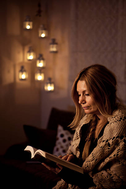 istock Young woman reading a book by candlelight 457749439