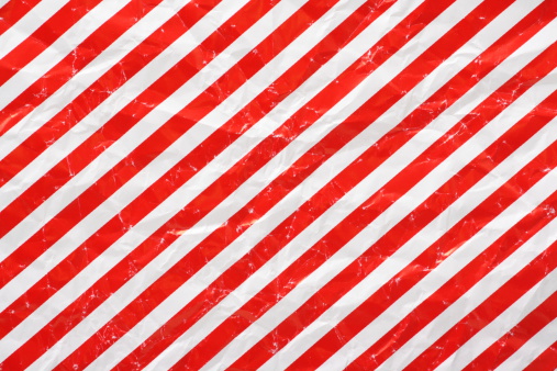 A crumpled sheet of Christmas wrapping paper in a red and white stripe pattern for use as a background