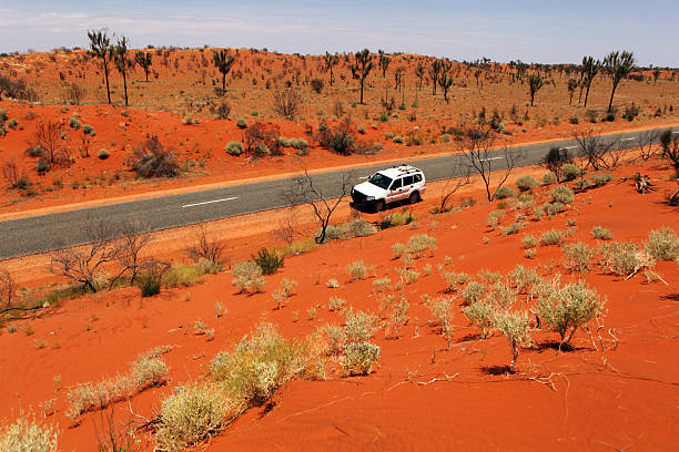 coche por la carretera rojo a outback australiano paisaje - outback 4x4 australia australian culture fotografías e imágenes de stock