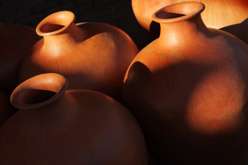 Vase jugs of terracotta clay pottery handmade in the Southwestern Native American tradition in sunlight and shadows.