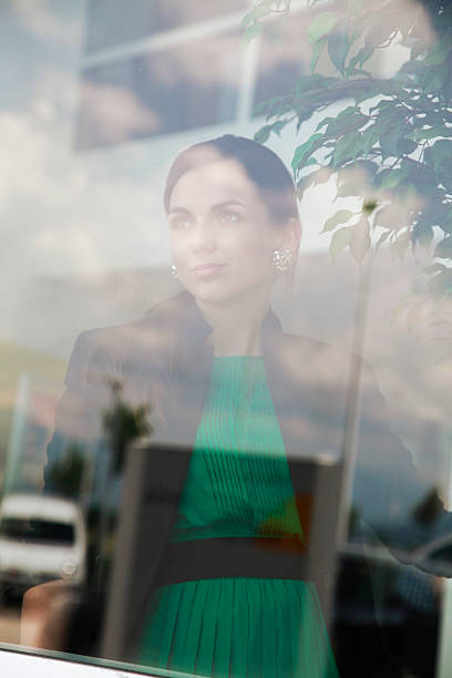 istock Pensive young woman looking through a window 457790859