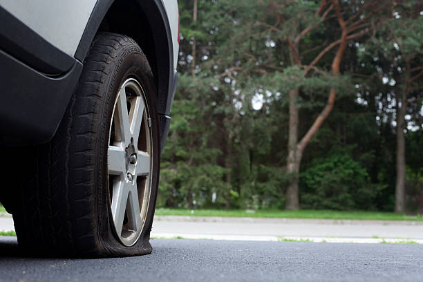 Close-up photo of a flat tire on a car on a road stock photo