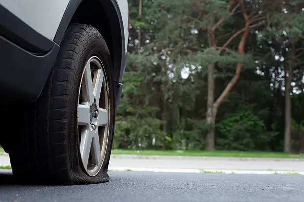 Photo of Close-up photo of a flat tire on a car on a road