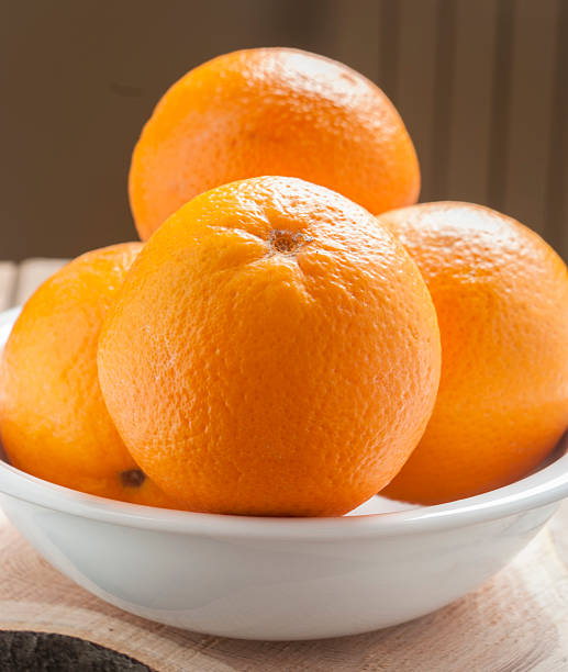 istock orange in white plate on wooden background 457819615