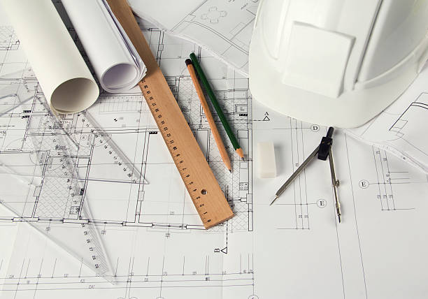 A bunch of engineering tools sprawled out on a blueprint rulers, pencils, compass, hardhat and an eraser on architectural blueprints. civil engineering stock pictures, royalty-free photos & images