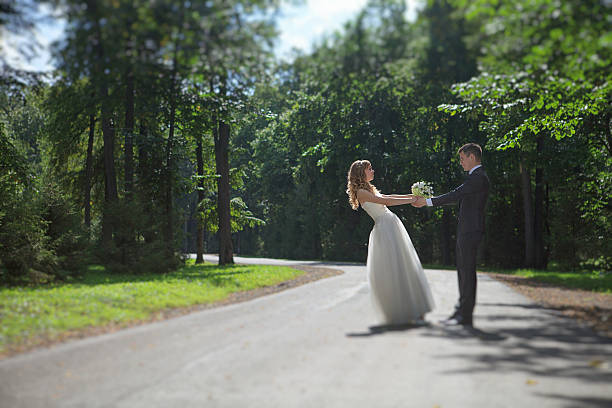 istock Newlyweds holding hands in a park on the road 457882735