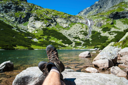 Hiker resting over the glacier lake with a waterfall in the background high in the mountains.