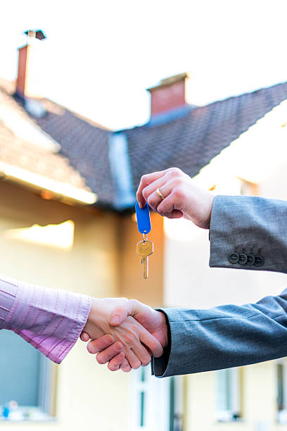 istock Handing  keys in front of house 457891631