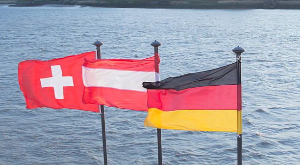 Swiss, Austrian and German flags A Swiss, Austrian and German flag on a river's edge swiss flag photos stock pictures, royalty-free photos & images