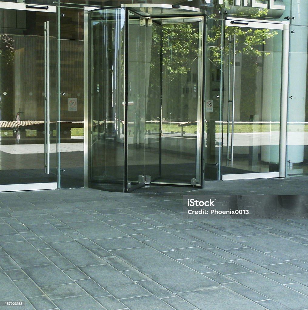Modern revolving door Office building exterior revolving door with green area reflected. Revolving Door Stock Photo