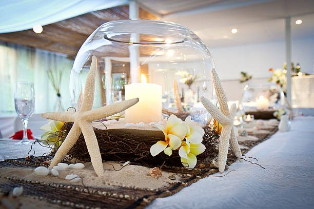 Beach theme wedding bridal table with candles, starfish, sand, shells and frangipani flowers