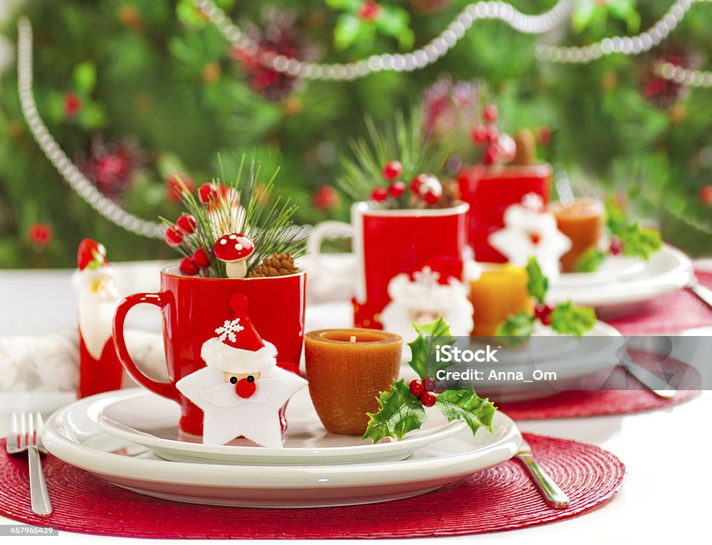 Christmas dinner decoration Photo of Christmas table decoration, festive dinnerware with candles and red cups for tea in decorated dinner room, luxury utensil, New Year party, Christmastime table setting, xmas decor Banquet Stock Photo