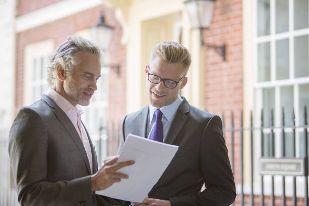 istock Businessmen looking at paperwork outdoors 457976859