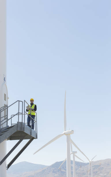 trabalhador em pé em turbina eólica na paisagem rural - wind power wind turbine safety technology - fotografias e filmes do acervo