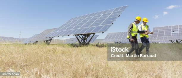 Workers Walking By Solar Panels In Rural Landscape Stock Photo - Download Image Now - Wind Turbine, Agricultural Field, Carbon Neutrality