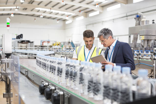 supervisor and manager watching plastic bottles on conveyor belt - essen und trinken stock-fotos und bilder