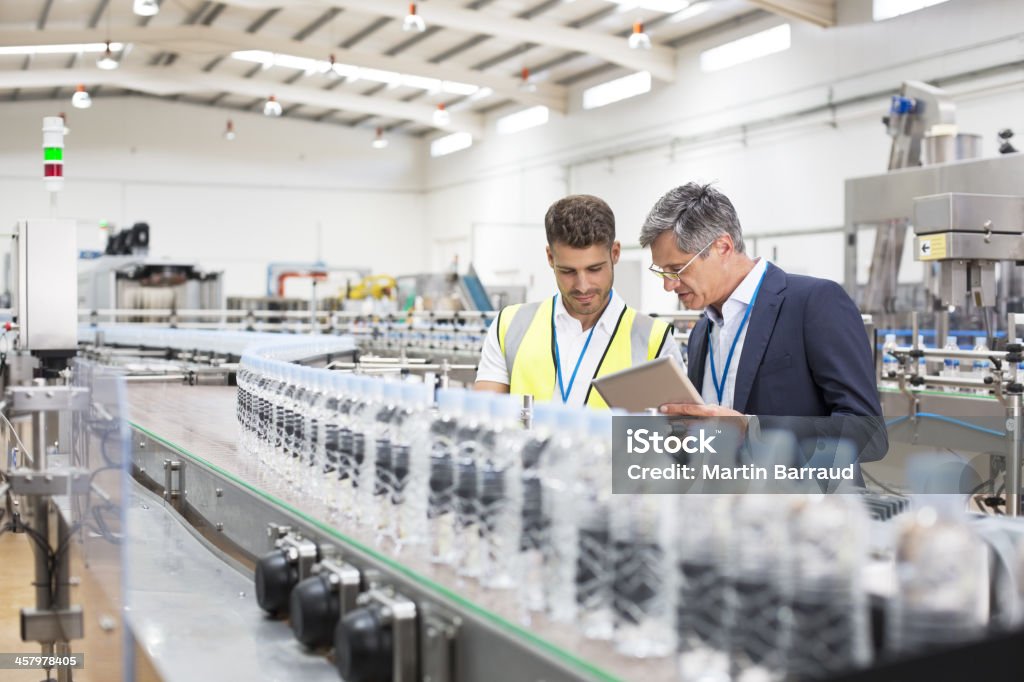 Supervisor and manager watching plastic bottles on conveyor belt  Factory Stock Photo