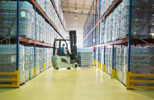 worker moving pallets with forklift in warehouse - water bottle plastic bottle bottling plant стоковые фото и изображения