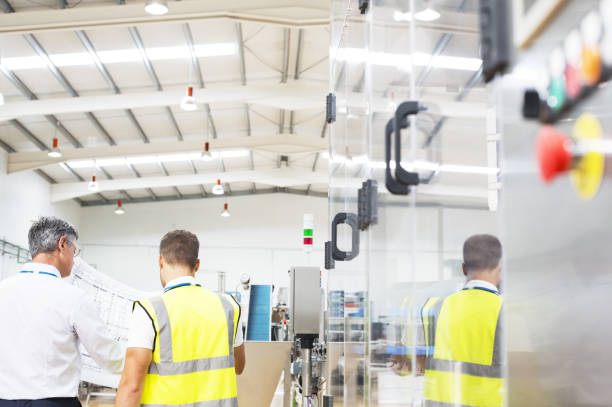 istock Supervisor and worker viewing blueprints in factory 457978609