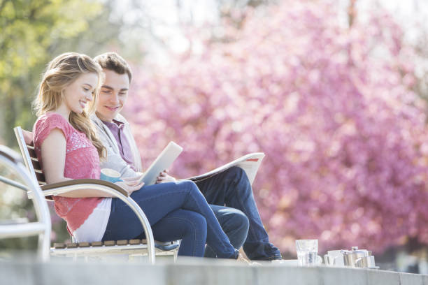 Portrait of a young businessman sitting on a bench and reading a newspaper in a park