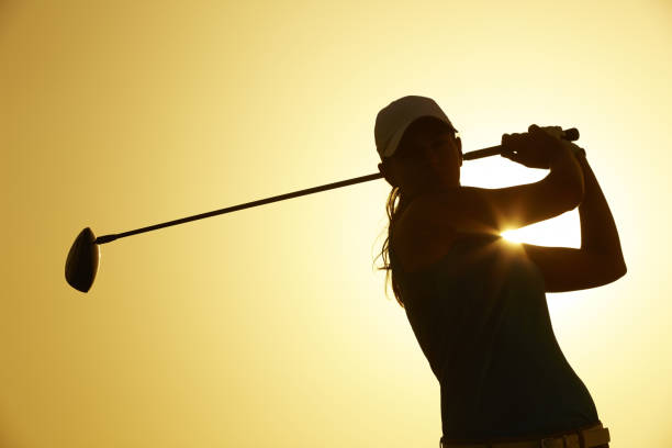 Silhouette of woman playing golf on course stock photo