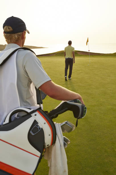istock Golfer and caddy nearing golf flag 457980045