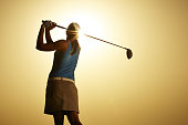 istock Sun shining behind woman swinging golf club 457980075