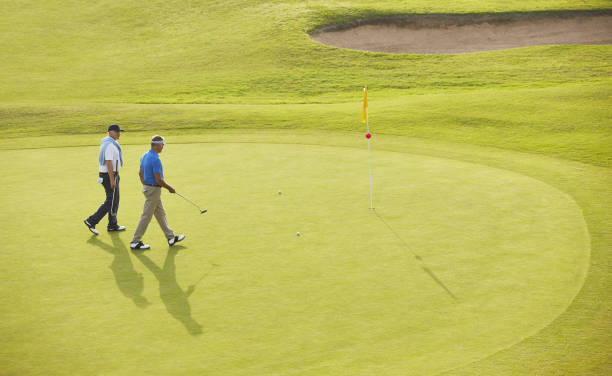 年配の男性のウォーキングをフラグとホールのゴルフコース - golf golf course putting men ストックフォトと画像