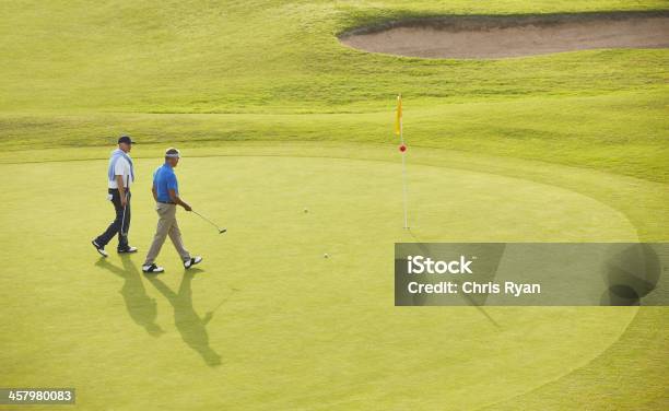 Senior Men Walking Toward Flag And Hole On Golf Course Stock Photo - Download Image Now