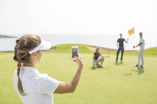 mulher fotografar os seus amigos no campo de golfe - golf four people young adult playing imagens e fotografias de stock