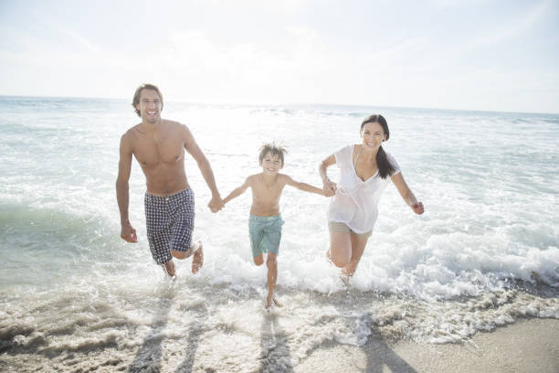 famille courir de surf sur la plage - ankle deep in water photos et images de collection