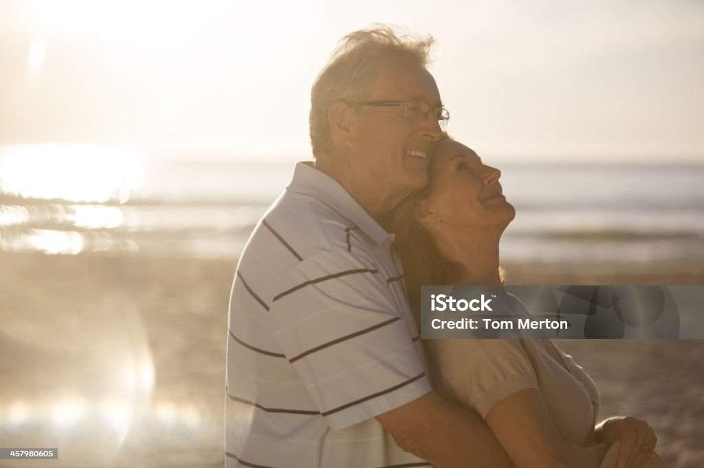 Older couple hugging on beach  Beach Stock Photo