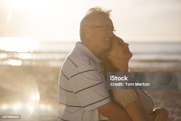 Older Couple Hugging On Beach Stock Photo - Download Image Now - Beach, Sun, Retirement