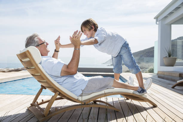 abuelo y nieto jugando en la piscina - wealth fotografías e imágenes de stock
