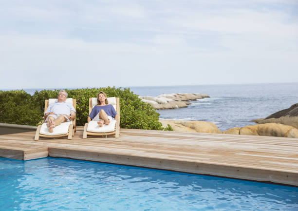 年配のカップルリラックス、プールサイドでの - deck chair ストックフォトと画像