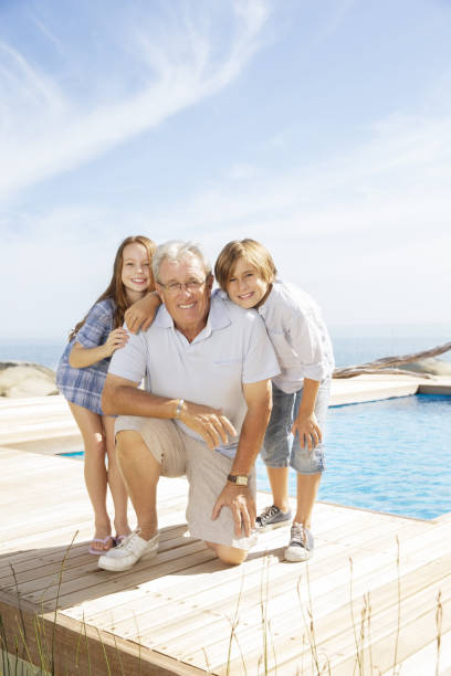 istock Grandfather and grandchildren smiling at poolside 457980831