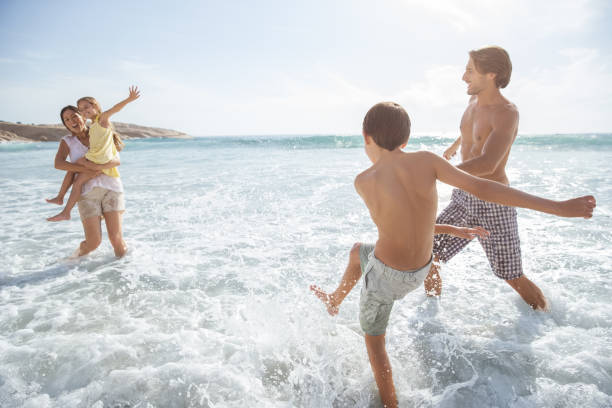 istock Family playing together in waves on beach 457980981