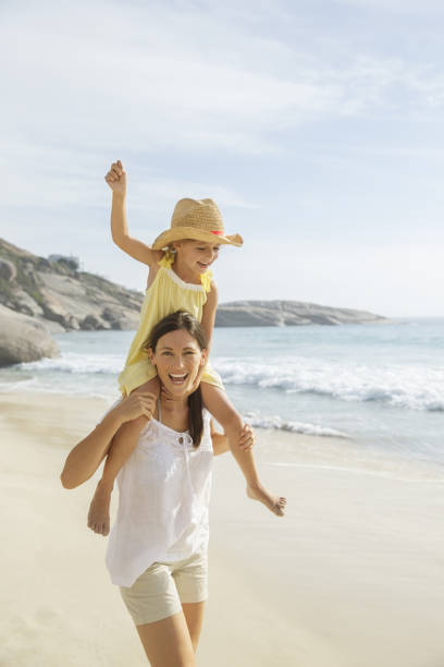 istock Mother carrying daughter on shoulders on beach 457981113