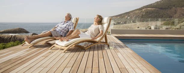 istock Older couple relaxing in lawn chairs by pool 457981223