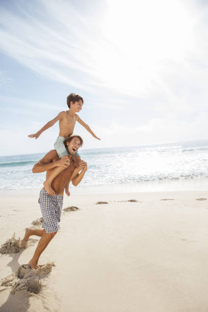 padre e figlio che giocano sulla spiaggia - men beach running shirtless foto e immagini stock