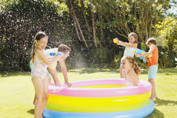 padre y niños jugando con pistolas de agua en el patio - pistola de agua fotografías e imágenes de stock