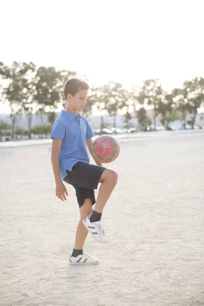 istock Boy kneeing soccer ball in sand 457984351