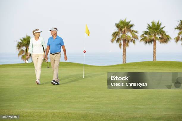 Senior Couple Walking On Golf Course Stock Photo - Download Image Now - Golf, Senior Couple, Vitality