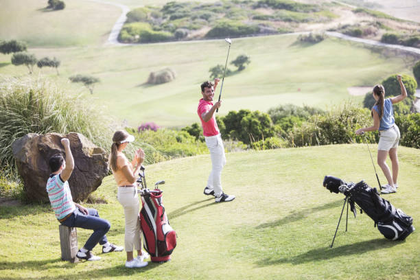 amigos teeing off no campo de golfe - golf four people young adult playing imagens e fotografias de stock